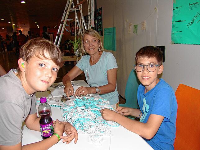 Lehrerin Elke Gutenkunst (Mitte) hilft David (rechts) bei seinem Makramee-Projekt. Dessen Mitschüler Philipp schaut neugierig zu.