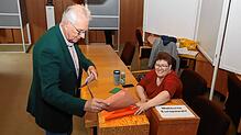 Rainer Wittmann (links) wirft seinen Umschlag mit den Stimmzetteln für die Kommunalwahl in die Wahlurne, während eine Wahlhelferin ...
