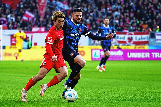 Freiburgs Ritsu Doan verteidigt den Ball im Zweikampf gegen Heidenheims Marnon Busch und bereitet damit den Führungstreffer des SC ...