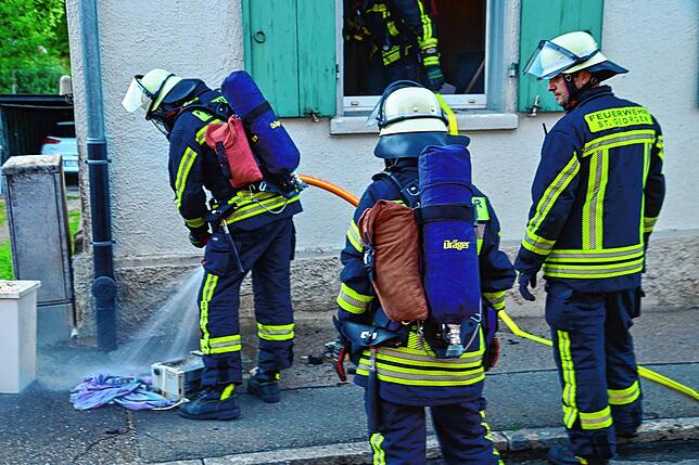 Ein Feuerwehrmann löscht den noch glimmenden Grill, der möglicherweise den Brand verursacht hat.