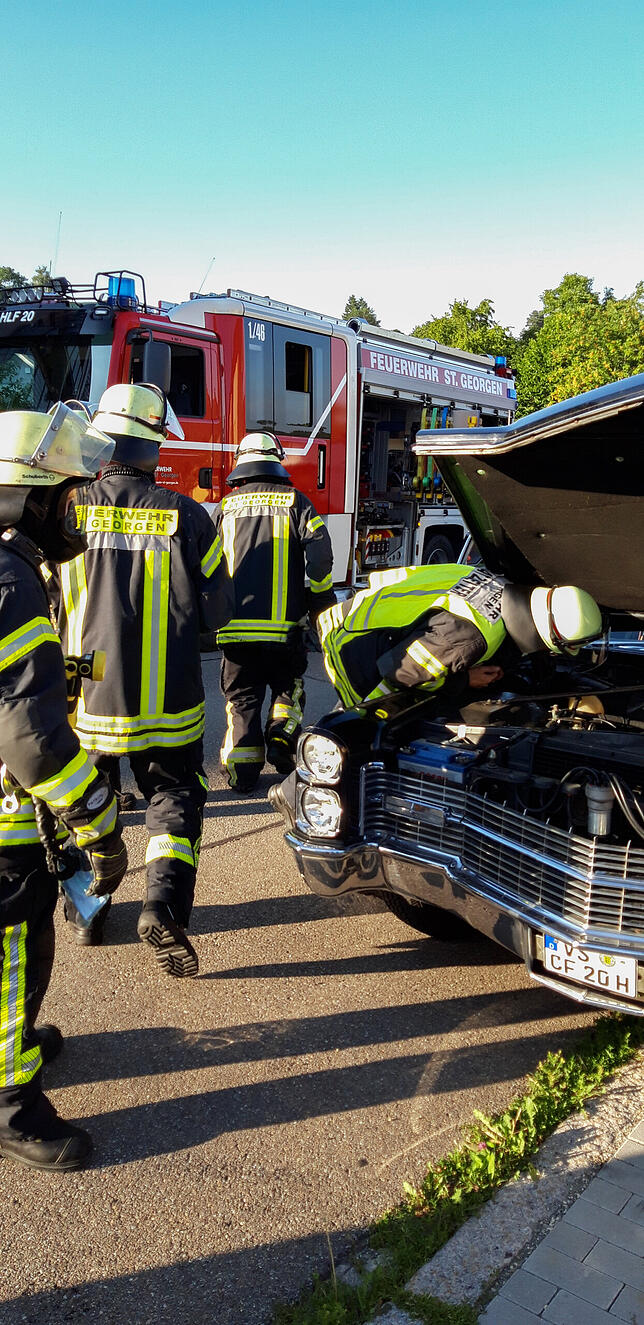 Die Feuerwehr inspiziert den Motorraum des Fahrzeugs, dessen Fahrer Rauchentwicklung festgestellt hat.