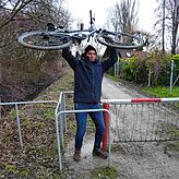 Andreas Schneider hievt sein Rad über eine Sperre. Er muss den Umweg nehmen, weil die Brücke am Seeuferweg in Stromeyersdorf abgerissen ist.
