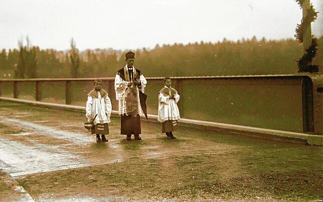 Dieses Foto von einem einsamen katholischen Geistlichen und seinen Ministranten, einer trägt den Weihwasserkessel, stammt vom ...