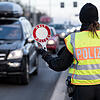 Eine Polizistin winkt ein Fahrzeug von der Straße zu einer Kontrollstelle auf den Standstreifen.