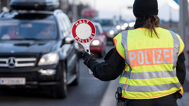 Eine Polizistin winkt ein Fahrzeug von der Straße zu einer Kontrollstelle auf den Standstreifen.