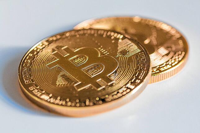 Zwei Bitcoin-Münzen liegen auf einem Tisch.
