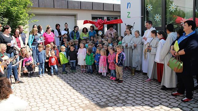 Pfarrer Manuel Grimm (rechts mit Ministranten) weiht die neuen Räumlichkeiten der Kinderkrippe ein. Die Kleinen singen ein Lied zum Festtag.