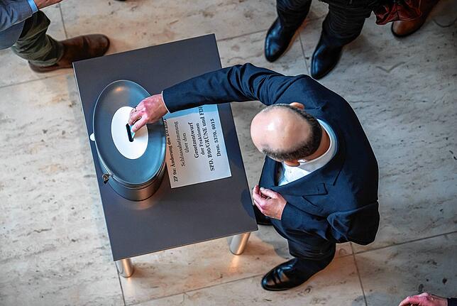 Bundeskanzler Olaf Scholz (SPD) wirft seine Stimmkarte bei der namentlichen Abstimmung im Bundestag ein.