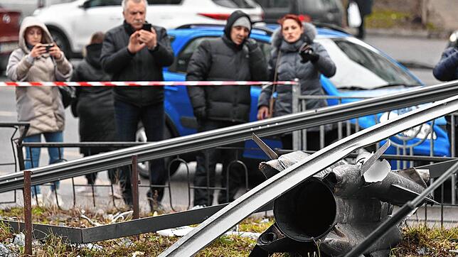Menschen in Kiew schauen sich die Reste einer Bombe an, die hinter Absperrband liegt. Kiews Bürger wurden vom Lärm der Bomben auf die ...