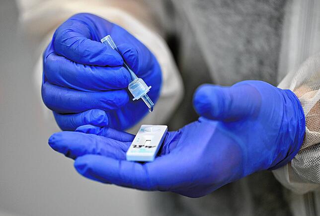 Ein Helfer verarbeitet eine Probe für einen Corona-Schnelltest.