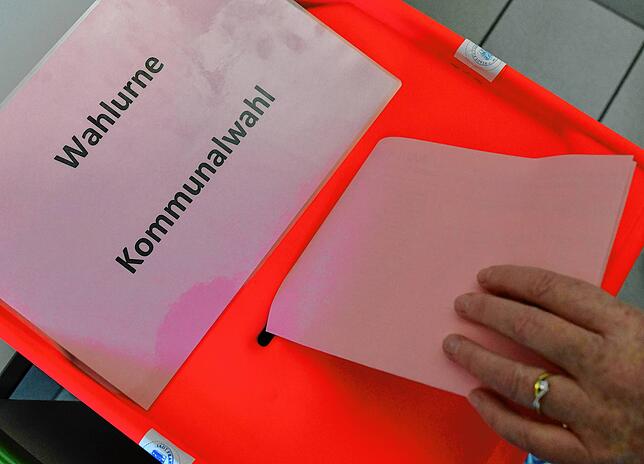 Dieses Symbolbild zeigt wie eine Wählerin ihren Stimmzettel bei einer früheren Kommunalwahl in Brandenburg in die Wahlurne steckt.