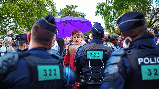 Eine Frau ohne Maske spricht in Paris während einer Anti-Masken-Demonstration mit französischen Bereitschaftspolizisten.