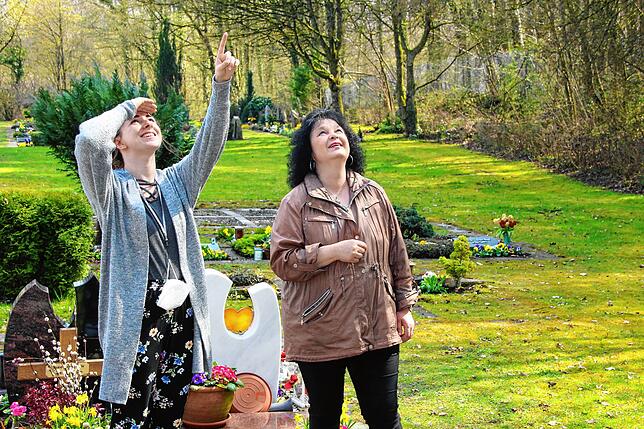 Melanie Breyer und Manuela Walter schauen zu den Bäumen am Friedhof hinauf. Hier blieb vor einem Jahr ein Ballon hängen.
