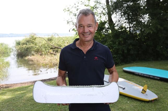 Ulf Meßmer zeigt einen Querschnitt durch ein Hardboard, das aus beschichtetem Styropor besteht. Im Hintergrund der Einstieg ins Wasser ...