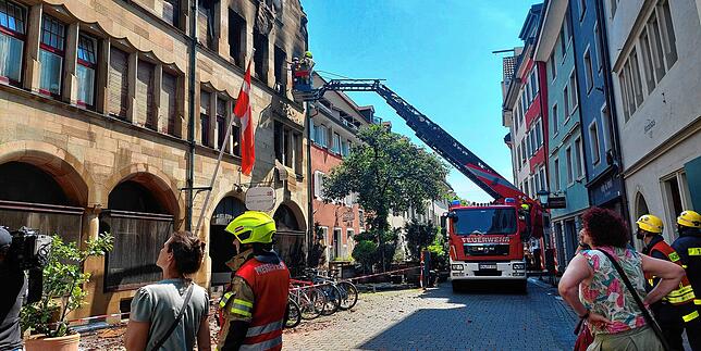 (Archivbild) Zur Mittagszeit bekämpft die Feuerwehr weiterhin den Brand. Konstanzer stehen fassungslos vor dem historischen Gebäude an ...