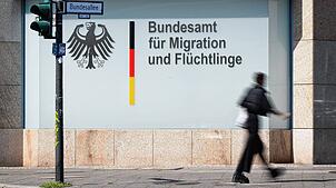 Ein Mann läuft vor dem Schriftzug „Bundesamt für Migration und Flüchtlinge“ in Berlin entlang.