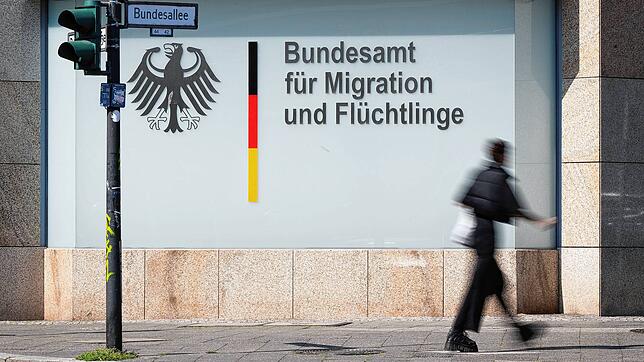 Ein Mann läuft vor dem Schriftzug „Bundesamt für Migration und Flüchtlinge“ in Berlin entlang.