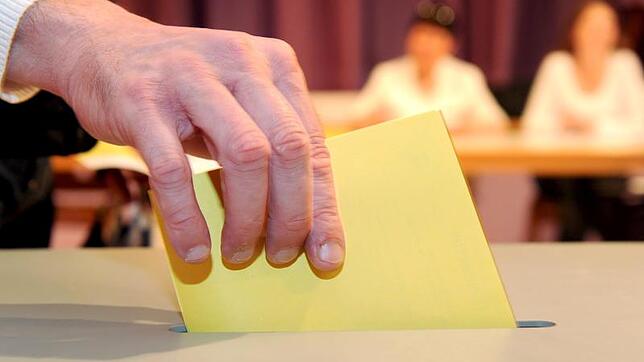 Ein Wahlzettel wird in eine Wahlurne gesteckt. (Symbolbild)