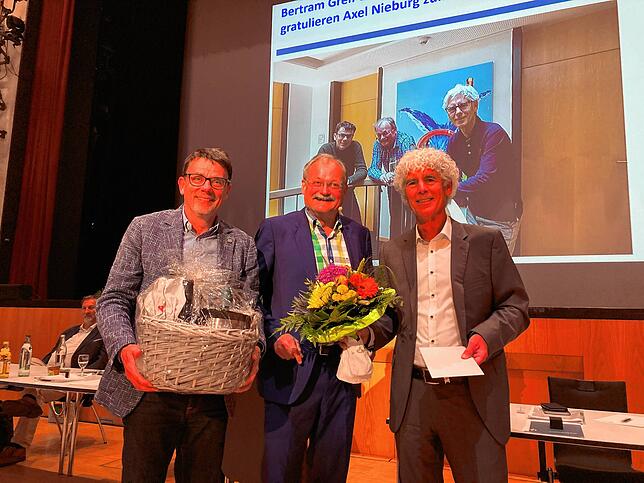 Vorstandskollege Jörg Müller (links) und Aufsichtsratsvorsitzender Bertram Greif (rechts) gratulieren Axel Nieburg zu 25 Jahren im Vorstand.
