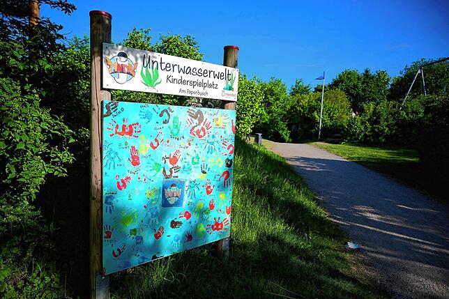 Ein Schild mit der Aufschrift “Unterwasserwelt – Kinderspielplatz„ steht an einem der Zugänge zum Spielplatz im Sauerland. Auf dem ...