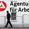 Ein Mann geht am Logo der Arbeitsagentur vorbei. (Symbolbild)