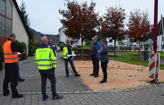 Vertreter der Gemeinde und von Baufirmen stehen an einer Kiesfläche, die Ersatzparkplätze für Kunden der Geschäfte in der Hauptstraße ...
