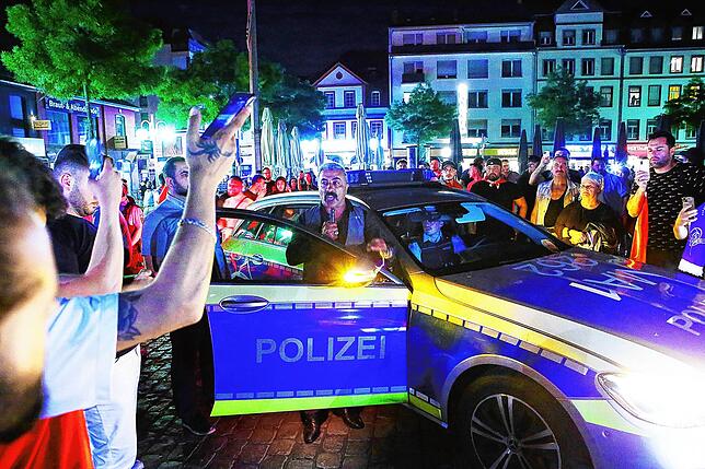 Die Polizei ist in der Mannheimer Innenstadt im Einsatz, während Menschen um ein Polizeiauto stehen. Nach Bekanntgabe des Sieges von ...
