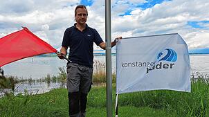 Jan Blessing, Schwimmmeister im Konstanzer Strandbad Hörnle, zeigt die zwei wichtigsten Flaggen, die im Schwimmbad am Bodenseeufer wehen ...