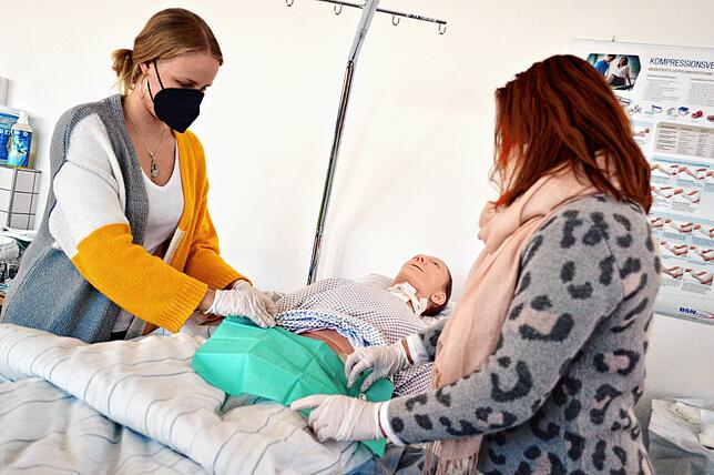 Laura Schell (links) und Iliyana Hrisdova zeigen anhand einer Puppe, wie man Wunden versorgt. Für beide Frauen ist der Pflegeberuf eine ...