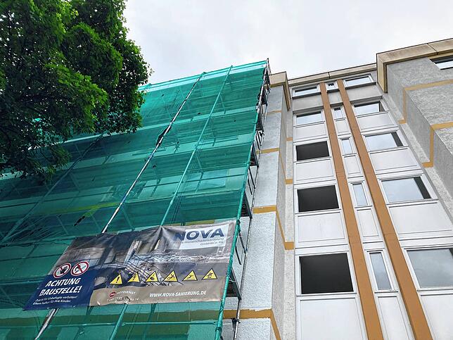 Das Gebäude von der Eingangsseite: Die Fassade ist noch verhüllt, mehrere Stockwerke haben im jeweiligen Flur noch keine neuen Fenster.
