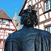 Beim Blick über die Schulter des Stauferkönigs Friedrich II sieht man den Glockenturm der Stadtkirche St. Jakobus zwischen den ...