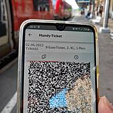 Ein Bahnfahrer hält im Bahnhof Waldshut ein Handy mit dem Neun-Euro-Ticket.
