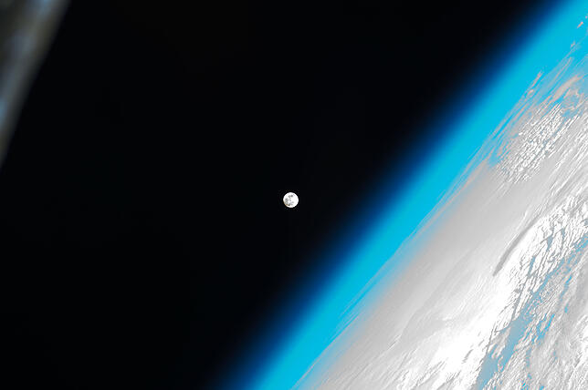 Die bläulich schimmernde Erd-Atmosphäre. Dahinter der Vollmond. Bild: NASA
