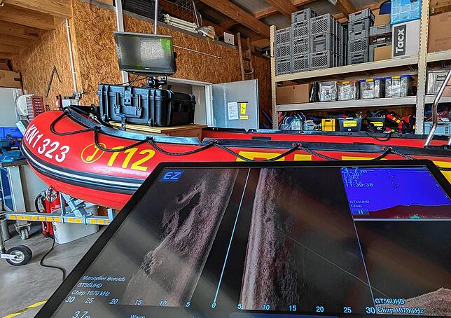 Das Sonar-Gerät mit kleinem Monitor steht auf dem Boot. Der große Bildschirm im Vordergrund zeigt ein Demo-Video.
