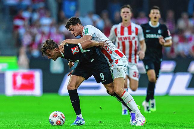 Lucas Höler (l, SC Freiburg) und Eric Martel (1. FC Köln) kämpfen um den Ball.