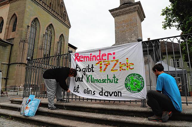 Sharon Hammerschick und Manuel Oestringer hängen im Klimacamp ein Banner auf.