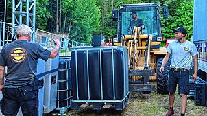 Millimeterarbeit leisten hier Bernd Höfler (links), Matthias Moosmann und David Moosmann (im Radlader), um das Bühnenequipment präzise ...