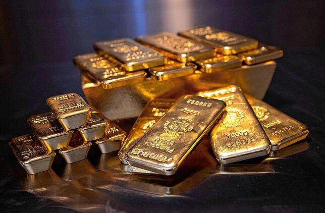 Goldbarren in unterschiedlicher Größe liegen bei einem Edelmetallhändler in einem Tresor auf einem Tisch.