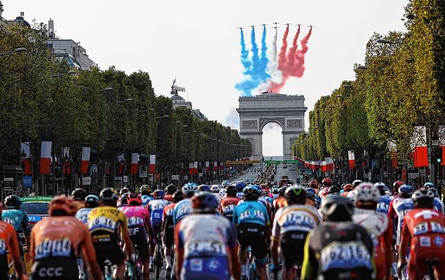 Flugzeuge der Kunstflugstaffel „Patrouille de France“ zeichnen die französische Nationalflagge über dem Arc de Triomphe, während das ...