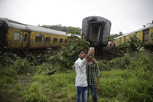 Jungen in Indien machen ein Selfie vor dem Bahngleis, auf dem zuvor ein Zug entgleiste.
