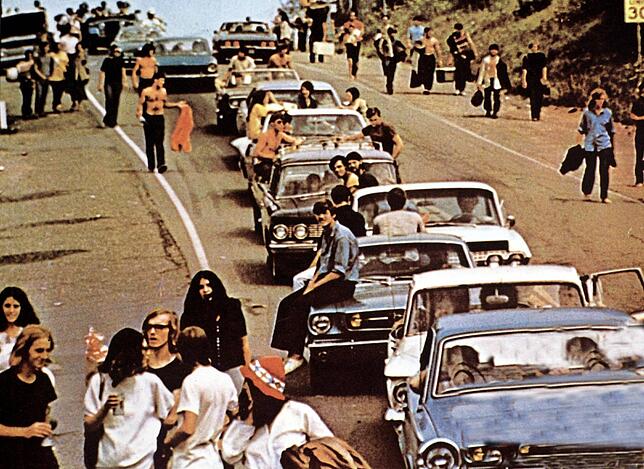 Besucher zu Fuß oder in Straßenkreuzern auf dem Weg zum legendären Rockfestival von Woodstock 1969.