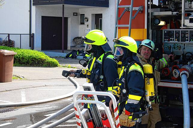 Feuerwehrleute in Atemschutzausrüstung kontrollieren die Temperatur des Gebäudes, in dem es gebrannt hat.