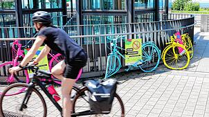 Eine Radfahrerin fährt an den „Crash Bikes“ am Parkhaus am See vorbei.
