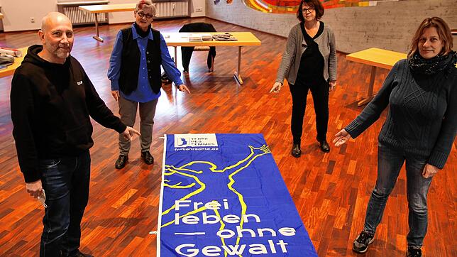 Erstmals hängt am Pfarrhaus eine Fahne zur Aktion &bdquo;Nein zu Gewalt an Frauen&ldquo;. Pfarrer Vogel (von links), Eva Wernert (Terre ...