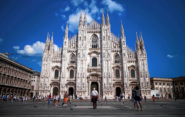 Menschen gehen über den Piazza del Duomo vor dem Mailänder Dom.