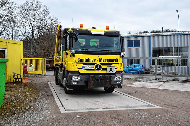 In der Einfahrt befindet sich die Waage, auf der gerade ein Firmenlaster steht, der einen Container anliefert.