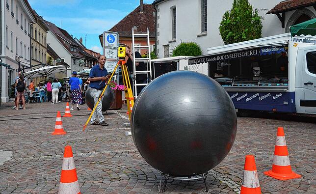 David Fuchs nimmt in der Markdorfer Marktstraße Maß für den geplanten neuen Brunnen. Hier im Juli 2024.
