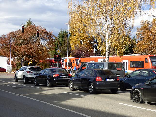 Am Bahnübergang Gutenberg-/Ensisheimer Straße fährt ein Zug vorbei. Die Schranken sind geschlossen, für die Rechtsabbieger in der ...