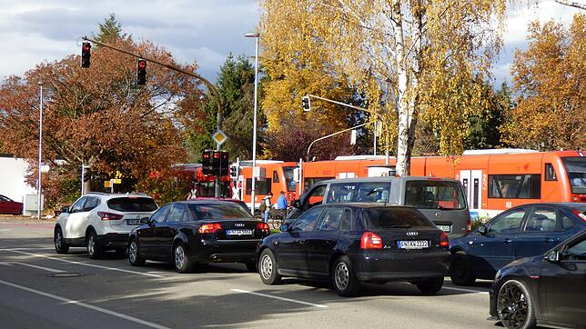 Am Bahnübergang Gutenberg-/Ensisheimer Straße fährt ein Zug vorbei. Die Schranken sind geschlossen, für die Rechtsabbieger in der ...