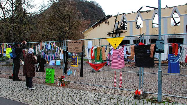 Passanten betrachten vor dem Zaun die Ruine der ehemaligen Scheffelhalle. Viele Singener bezeugen ihre Trauer, indem sie Kerzen ...